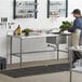 A woman using a Regency stainless steel work table with sink in a professional kitchen.