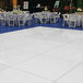 A white Palmer Snyder portable dance floor with silver trim surrounded by white tables and chairs.