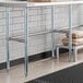 A Regency stainless steel work table with a Regency metal shelf holding a stack of brown bags.