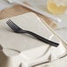 A black Eco-Products 100% post-consumer recycled plastic fork on a white cloth.