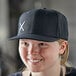 A woman wearing a black Mercer Culinary snapback hat with a small white logo.