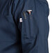 A close up of a Uncommon Chef navy long sleeve chef coat with pockets.