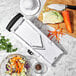 A OXO V-Blade Mandoline slicer on a marble surface with shredded vegetables in a bowl.