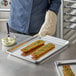 A person using a Choice half size aluminum bun pan to cut bread.