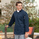 A man wearing a Uncommon Chef Orleans navy long sleeve chef coat.