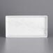 A white rectangular melamine tray with a marble design.