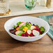 A matte white American Metalcraft melamine bowl filled with salad.