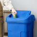 a hand putting a cup into a blue trash can