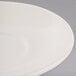 A close up of a Tuxton Reno eggshell white saucer with a rim.