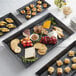 A rectangular black melamine tray with a variety of food on it.