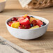 A white melamine bowl filled with assorted fresh fruit pieces.