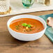An American Metalcraft Cloud Melamine bowl of soup with basil leaves and croutons.