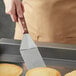 A person using a Dexter-Russell Traditional pancake turner to flip a pancake on a pan.