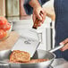 A person using a Mercer Culinary Praxis turner to flip food in a pan.