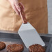 A person using a Dexter-Russell hamburger turner to cook hamburger patties on a grill.