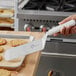 A hand with a white Mercer Culinary Millennia turner lifting a cookie from a tray.