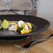 A RAK Porcelain grey and black wide rim porcelain plate with food on it on a table.