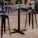 A square bar height table with a smooth paladina finish and a black cross base plate.