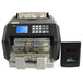 A black Royal Sovereign electronic bill counter with a digital display counting several dollar bills.