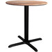 A Lancaster Table & Seating round wooden table with a black base.