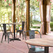 A Lancaster Table & Seating Excalibur dining table with a textured Yukon oak finish on a patio with chairs.