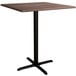 A Lancaster Table & Seating square bar height table with a walnut top and black base plate.