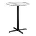 A round bar height table with a smooth white marble-look top and a black cross base plate.