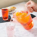 A hand pouring Fineline clear plastic pitcher into a glass of pink liquid.