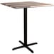 A Lancaster Table & Seating Excalibur square bar height table with a textured wooden top and black cross base.