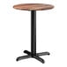 A round standard height table with a textured Yukon oak finish top and a black cross base plate.