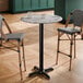 A round bar height table with a smooth Versilla finish and a black cross base plate.
