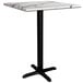 A Lancaster Table & Seating square counter height table with a white marble top and black cross base plate.