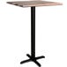 A Lancaster Table & Seating Excalibur square bar height table with a textured wooden top and black cross base.