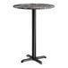 A round bar height table with a smooth dark finish top and a black cross base plate.
