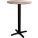 A Lancaster Table & Seating round wooden table with a black cross base.