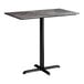 A rectangular bar height table with a smooth dark finish and a black cross base plate.