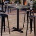 A rectangular bar height table with a smooth dark finish and a cross base plate.