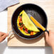 An OXO Good Grips silicone turner flipping an omelet in a pan.