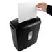 A hand putting a white sheet of paper into a black Royal Sovereign cross-cut shredder.