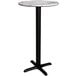 A Lancaster Table & Seating bar height table with a white marble top and black cross base.