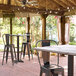A Lancaster Table & Seating bar height table with a smooth finish and cross base plate on a covered patio.