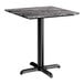 A square standard height table with a smooth dark finish and a black cross base plate.
