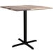 A Lancaster Table & Seating square table with a black cross base and wood top.