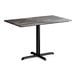 A rectangular standard height table with a smooth dark finish top and a black cross base plate.