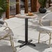 A round standard height table with a textured mixed plank finish and a black cross base plate.