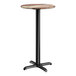 A round bar height table with a textured mixed plank finish top and a black cross base plate.