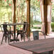 A Lancaster Table & Seating rectangular dining table with a textured walnut finish and cross base plate outside on a patio with chairs.