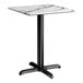 A square standard height table with a smooth white marble-like top and a black cross base plate.