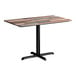 A rectangular standard height table with a textured mixed plank finish top and a black cross base plate.