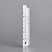 A close-up of a Taylor 1105J wall thermometer with a red dot on a gray surface.